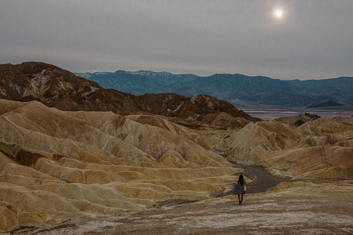 Woman enjoying the vast wilderness of Death Valley, looking at the horizon from the famous Zabriskie point.