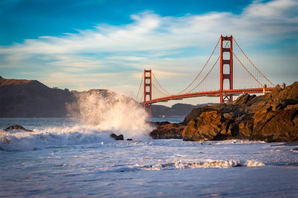 golden gate bridge and a crashing wave on the rocks in san francisco,california - healey imagens e fotografias de stock