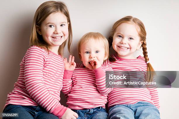 3 つの幸せなおそろいの姉妹一緒に座っている笑顔 - 1歳以上2歳未満のストックフォトや画像を多数ご用意 - 1歳以上2歳未満, 2歳から3歳, 3人