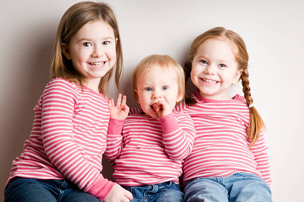 Three Happy, Matching Sisters Sitting Together and Smiling