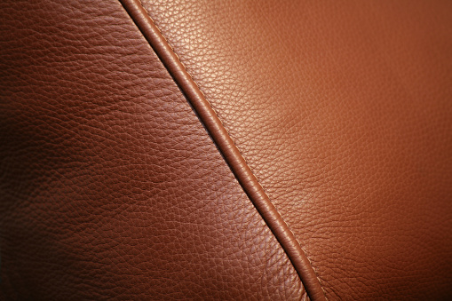 Texture of yellow genuine leather sewn with stitch close-up. Modern background, copy space