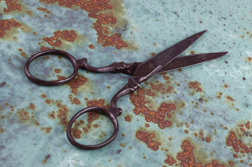 Vintage embroidery scissors on rusty metal background