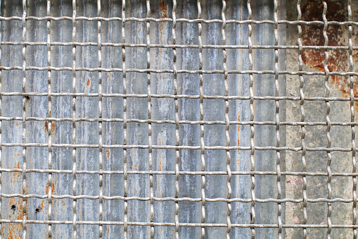 Grille grunge rusty metal zinc wall. Industrial Background and texture in retro concept. Square pattern Wire fence.