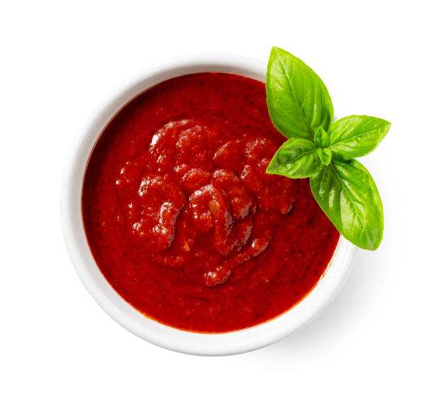 Tomato sauce and basil in a white bowl against a white background.
