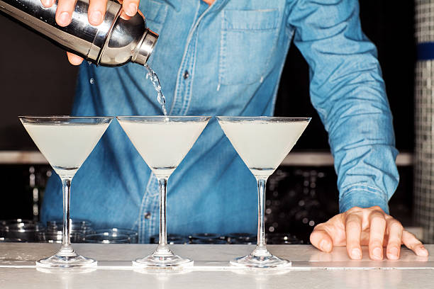 istock Bartender Pouring Cocktail Into Martini Glasses At Counter 174565664