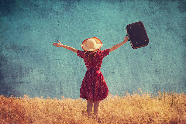 istock Redhead girl with suitcase at summer field 174565825