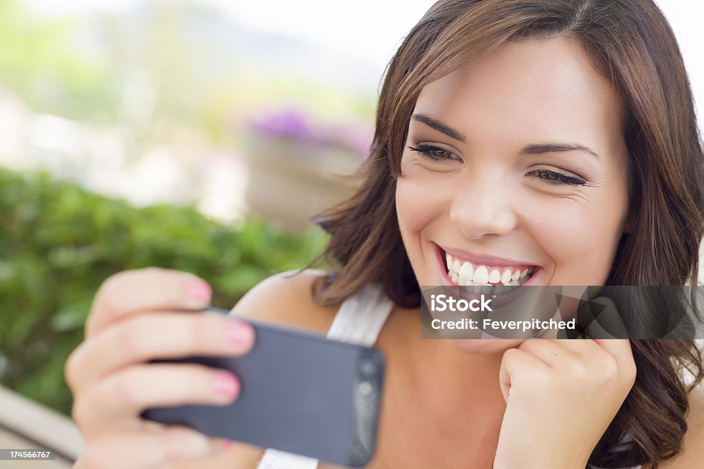 Young Adult Female Texting on Cell Phone Outdoors Attractive Smiling Young Adult Female Texting on Cell Phone Outdoors on a Bench. 20-29 Years Stock Photo