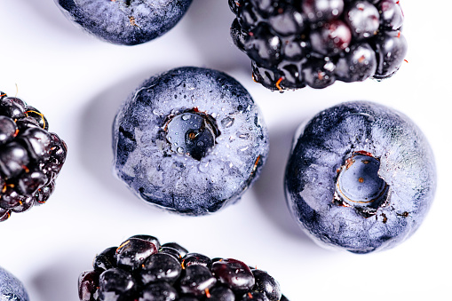 Front view of a group of mixed berries like blueberries, blackberries and raspberries with some mint leaves isolated on white background. Studio shot taken with Canon EOS 6D Mark II and Canon EF 100 mm f/ 2.8