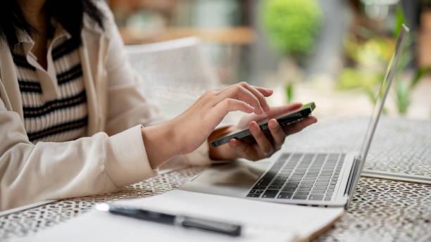 istock A woman sitting in an outdoor space and using her phone while working remotely from a coffee shop. 1745680873