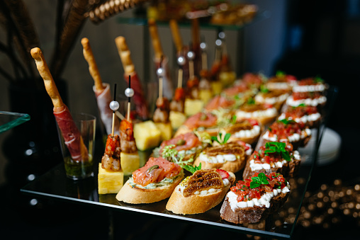 hors d'oeuvres on a glass table. Salsa, salmon, tomatoes, mozzarella, and a variety of cheese canapés. catered luxury.