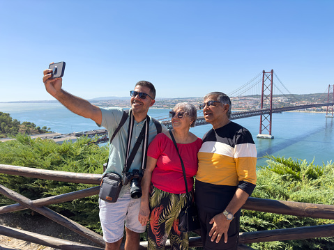 Adult son with elderly parents takes selfie at the viewpoint