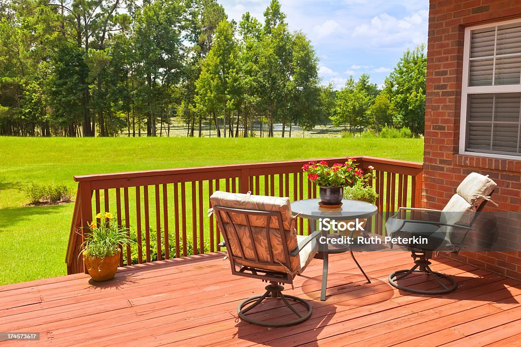 Backyard deck next to a green field Residential backyard deck overlooking lawn and lake Deck Stock Photo