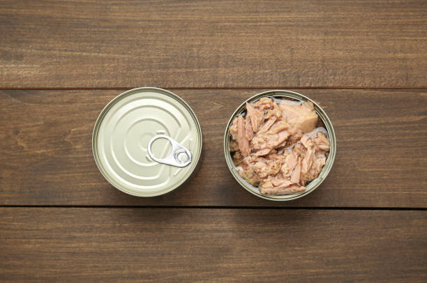 istock Tin cans with canned tuna on wooden table, flat lay 1745757714