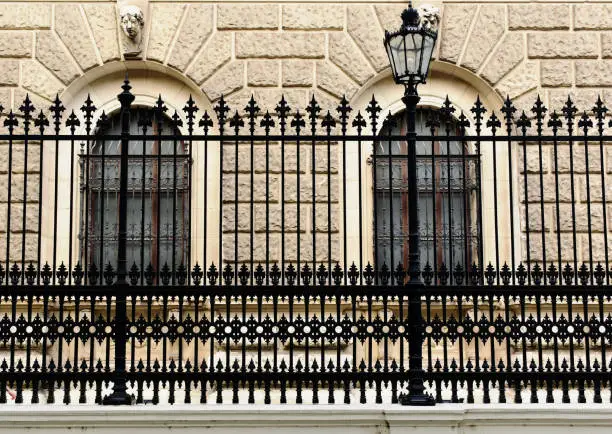 Photo of vintage black cast iron fence front view. soft stucco old classic exterior elevation. perspective view