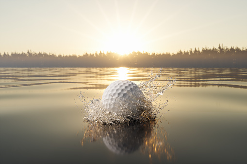 Close-up view Of Golf Ball Splashing In Water With Sunset View Background
