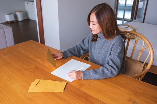 Portrait image of a young woman writing on a letter and envelopes