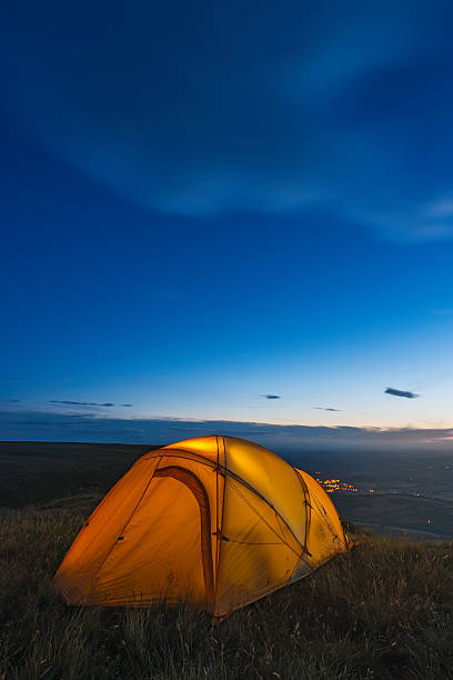 istock Bright orange tent camped high on hillside overlooking valley below 174581989