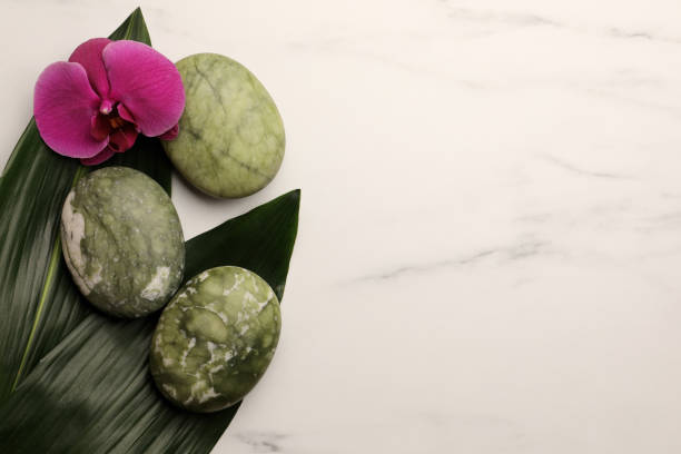 istock Beautiful spa composition with stones, flower and leaves on white marble table, flat lay. Space for text 1745820705