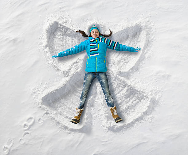 Snow Angel fun Young teenage girl creating a snow angel. snow angels stock pictures, royalty-free photos & images