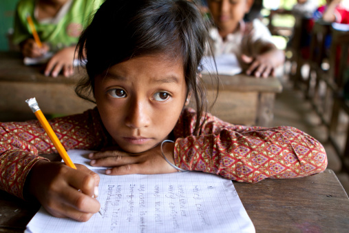 A young Asian girl studies hard her English writing skills (look at what she's writing down).