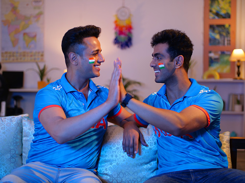 Two friends in a jersey - supporting team India, Indian men exchanging high fives for their team
