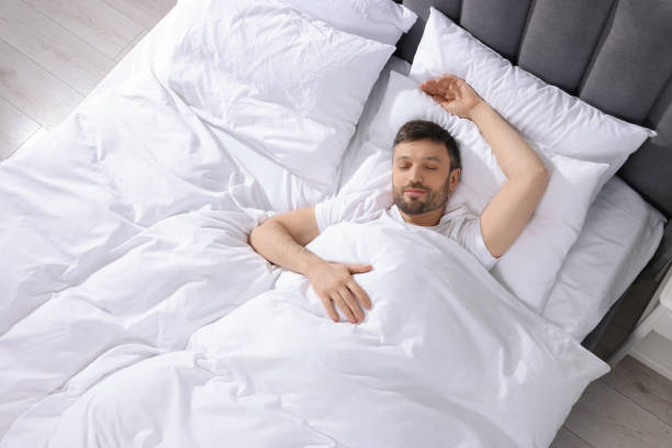 istock Handsome man sleeping in soft bed at home, top view 1745864366