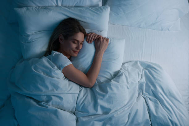 mulher dormindo na cama à noite, acima da vista. espaço para texto - boa noite - fotografias e filmes do acervo