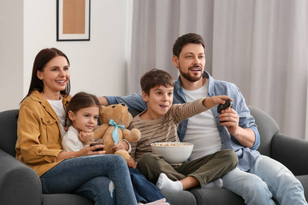 istock Happy family watching TV at home. Son changing channels with remote control 1745871276
