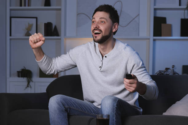 istock Emotional man watching TV on sofa at home 1745872349