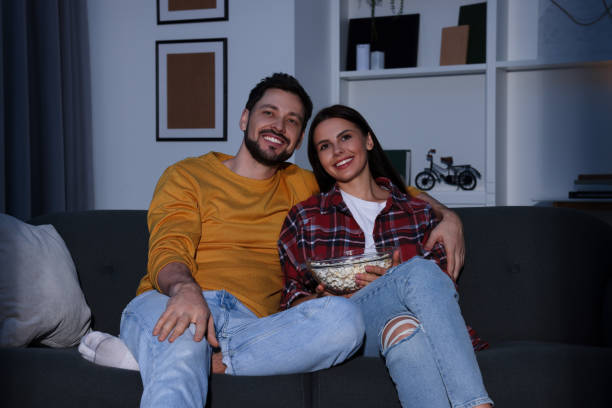 istock Happy couple watching TV at home in evening 1745873396