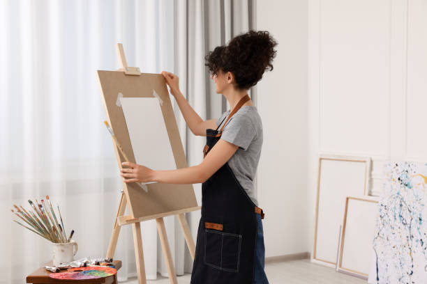 istock Young woman with brush adjusting easel in studio 1745880634