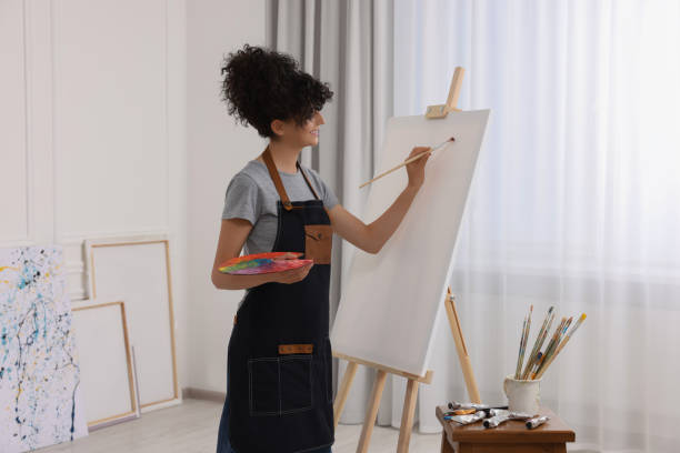 istock Young woman painting on easel with canvas in studio 1745881714
