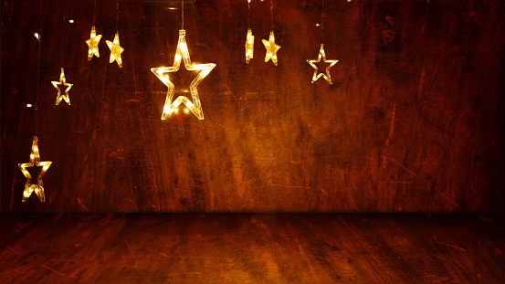 Dark brown colored wooden textured 3D or three dimensional horizontal blank Xmas or Diwali celebrations festive background, poster or wallpaper. Can be used as Christmas party wallpaper, backdrop, celebration, festive background, gift wrapping sheet. There are several stars lights hanging from the top leaving plenty of copy space.