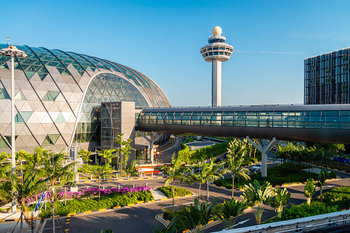 Changi Airport, Singapore - January 24, 2020: Changi Airport futuristic viewes with bridge between terminals at sunset time viewed through window