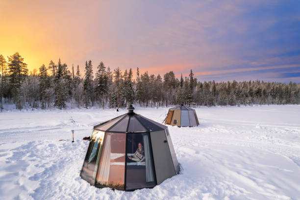 kobieta relaksująca się w ciepłym otoczeniu szklanego igloo patrząc na zamarznięty krajobraz pokryty śniegiem, jokkmokk, norrbotten, szwecja, szwedzka laponia, skandynawia - winter landscape sweden snow zdjęcia i obrazy z banku zdjęć