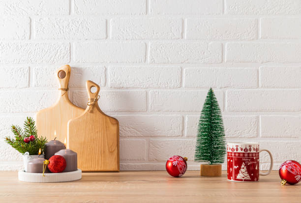 istock Red mugs with Christmas pattern, candle set, red ball and decorative Christmas tree on kitchen countertop. Festive kitchen background. minimalism. 1745921208