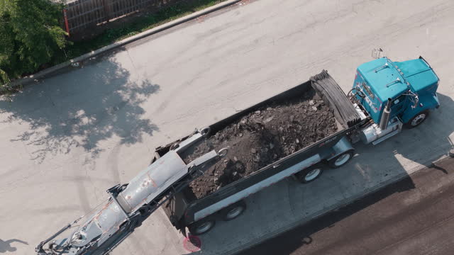 Group of construction workers Shredded old asphalt in to truck on parking lot and roadway. Top down shot