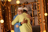 Father and son in skull caps embracing during Eid-Ul-Fitr
