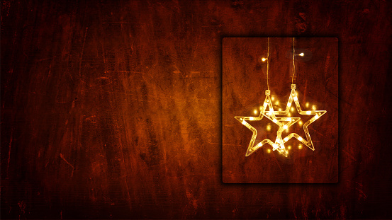 Dark brown colored wooden textured 3D or three dimensional horizontal blank Xmas or Diwali celebrations festive background, poster or wallpaper. Can be used as Christmas party wallpaper, backdrop, celebration, festive background, gift wrapping sheet. There are two stars lights hanging from the top in a frame leaving plenty of copy space.