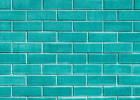 Brightly coloured brick wall in a soft pastel aqua green teal colour. An organic texture for use as a background in graphic design to create a modern, fresh urban style.