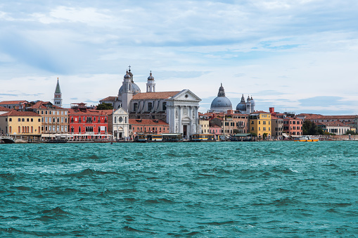 Panoramic view of colorful old buildings and Santa Maria del Rosario church along the Giudecca canal waterfront in Venice Italy.