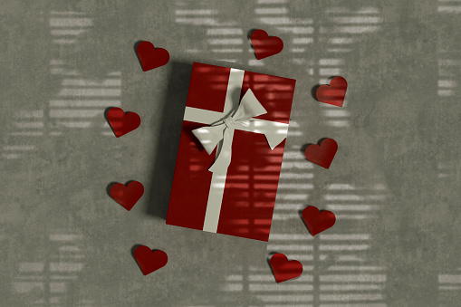 Gift box with heart shapes top view on gray background with light beam. Digitally generated image.