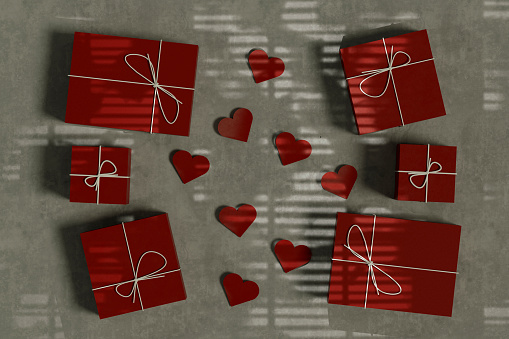 Gift boxes with heart shapes top view on gray background with light beam. Digitally generated image.