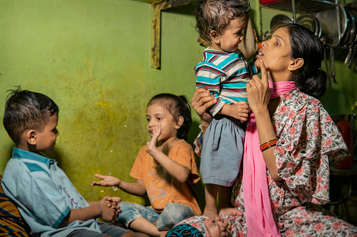 Indoor portrait of happy rural Indian pregnant woman with her three children at home.