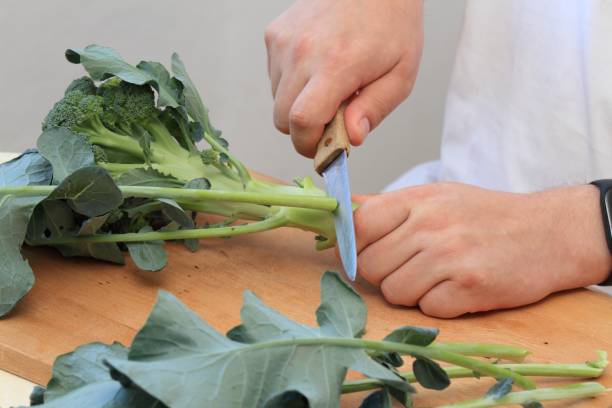 istock Man's hands cutting fresh raw broccoli leaves off 1745995181