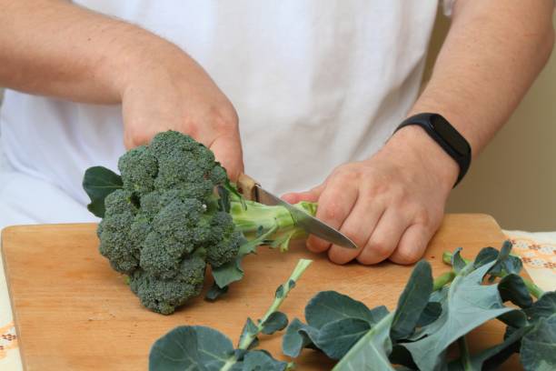 istock Man's hands cutting fresh raw broccoli leaves off 1745995705
