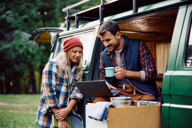 istock Happy couple using laptop while relaxing in camper trailer in the woods. 1745998979