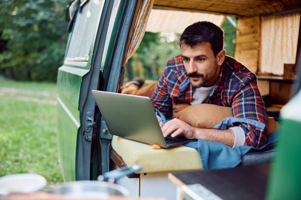 istock Male camper using laptop while relaxing in his van in nature. 1745999511