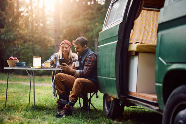 istock Happy couple using mobile phone while camping in the woods in autumn. 1746002313