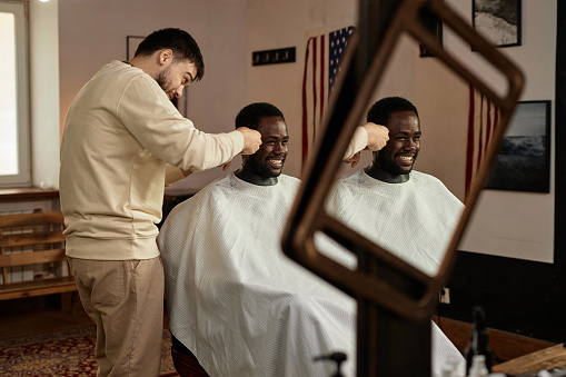 African American young man cutting his hair in barber shop